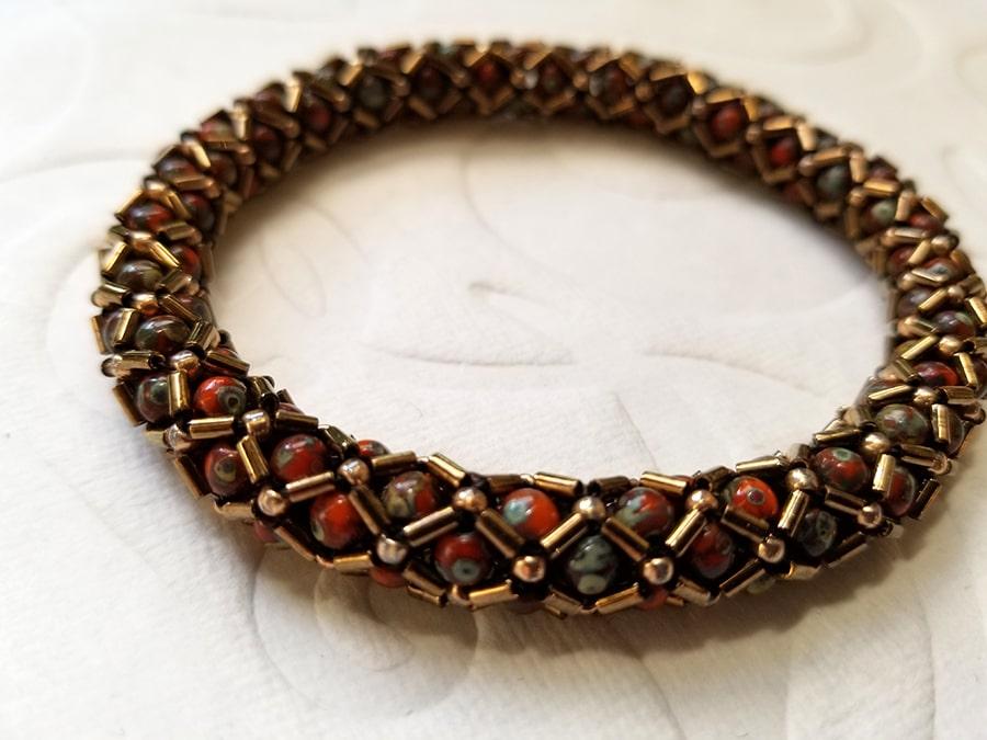 Bead stitched bangle in browns & red