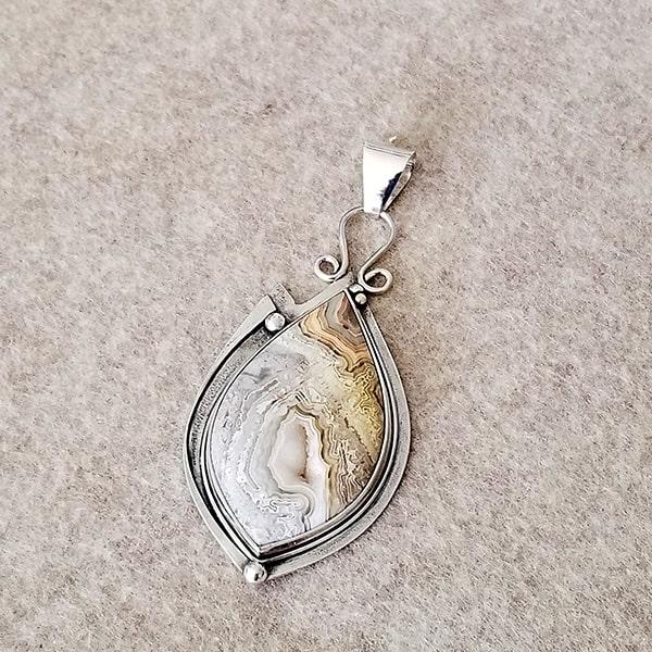 Cut and polished crazy lace agate teardrop pendant with a center druzy in a sterling silver bezel