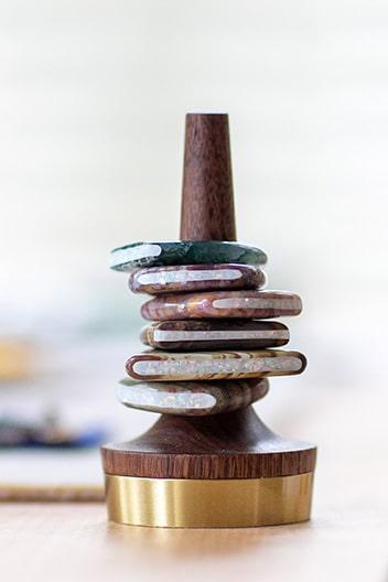 Stack of artisan stone rings with opal channel inlay on a wooden ring holder