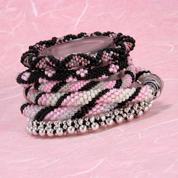 Stack of bead crochet bracelets in different patterns in pink, black, white, and silver