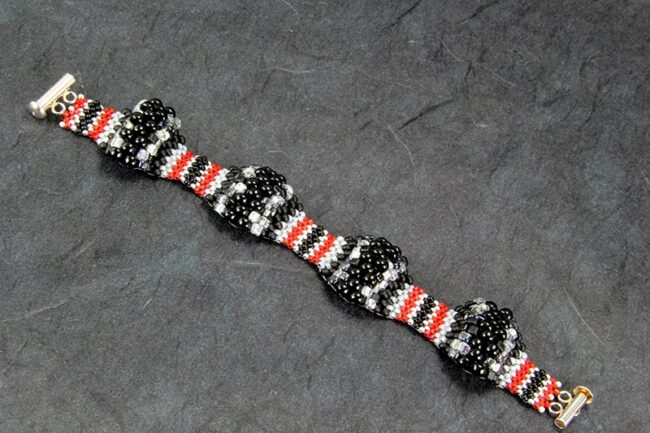 Peyote stitch bracelet with multiple size beads in black, red, and grey